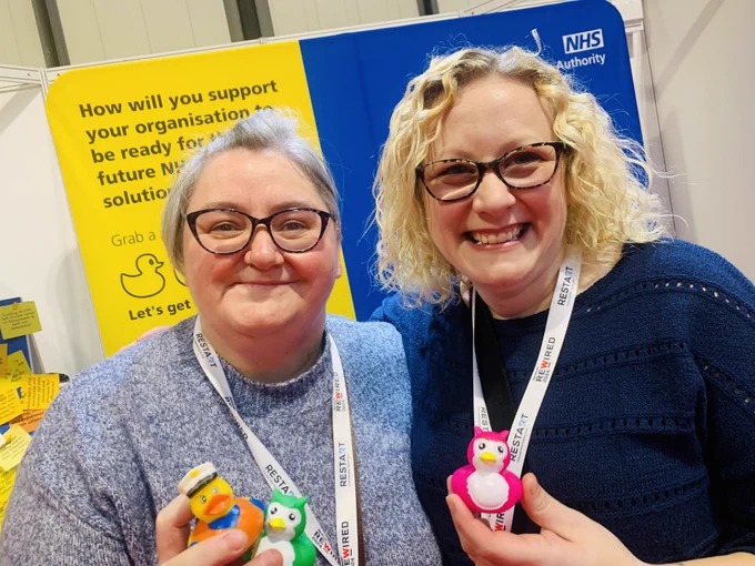 NHSBSA colleagues and visitors at Digital Health Rewired in Birmingham, stood in front of the stand holding rubber ducks.
