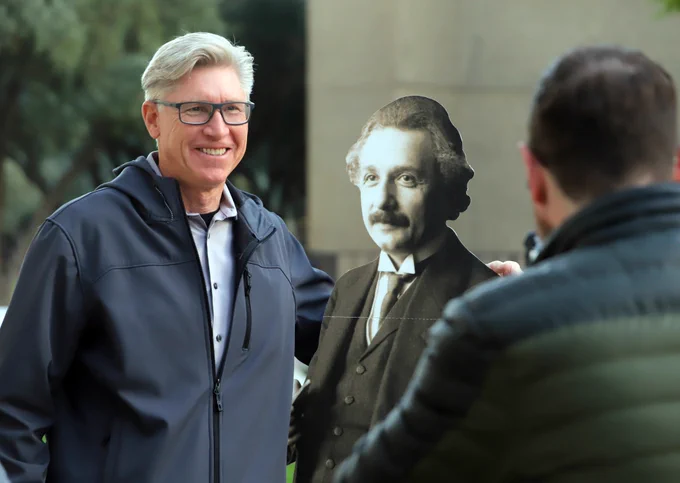 A man smiles as he poses for a photograph with a lifesize cardboard figure of Albert Einstein