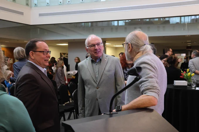 Three men engage in conversation.