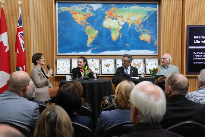 A woman speaks into a microphone on a panel with three other people.