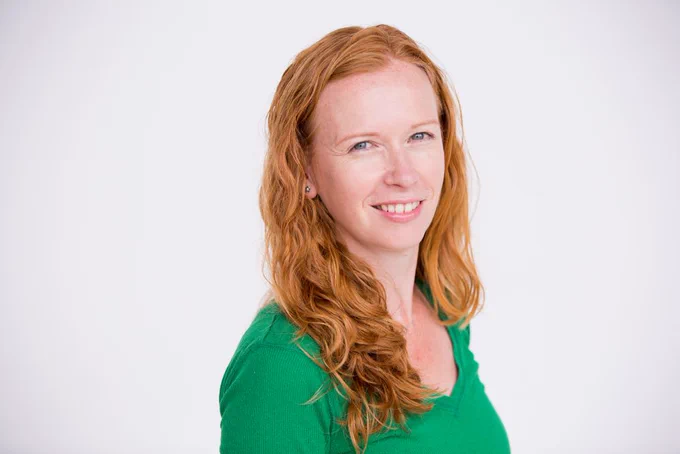 A person, wearing a green top, is smiling at the camera