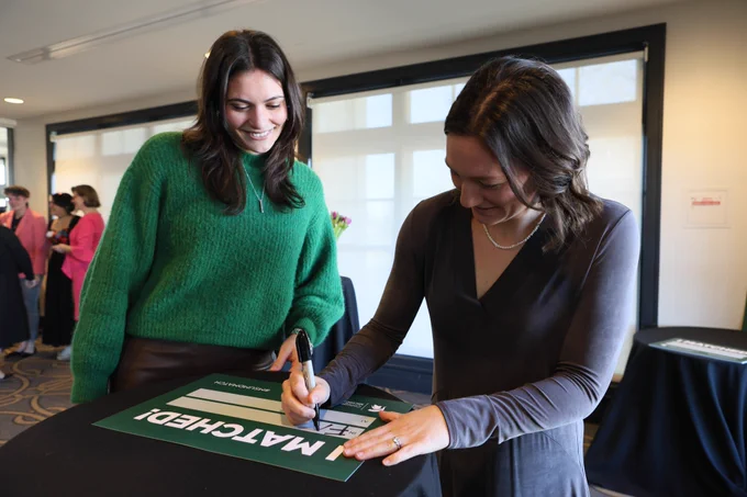 Two medical students filling out a Match Day sign to show their residency match