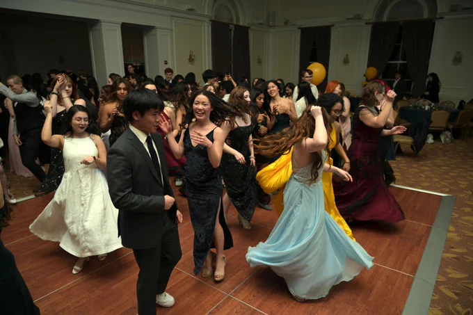 A large group of students dances in a ballroom.