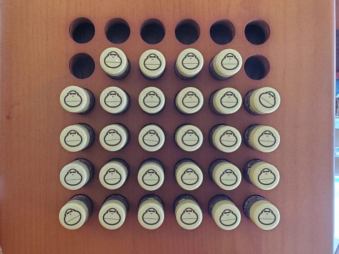 What looks like tubes of chapstick in holes. There is a 6×6 grid of holes. Top row is empty. 2nd row, the middle 4 are filled. The rest of the holes are filled.
