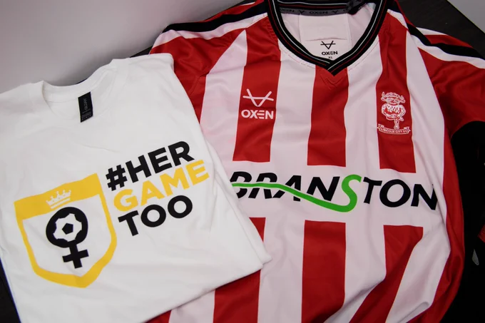 Her Game Too warm up shirt pictured with City's home kit.