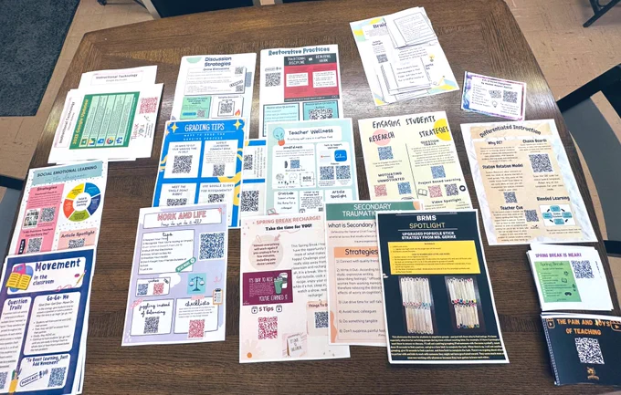 A tabletop covered with about a dozen different pieces of color printouts, each with QR codes and neat, colorful designs, alongside instructions for educators for self-directed learning.