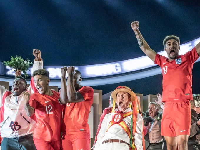 A group of young men in football kit jump in victory and shout.