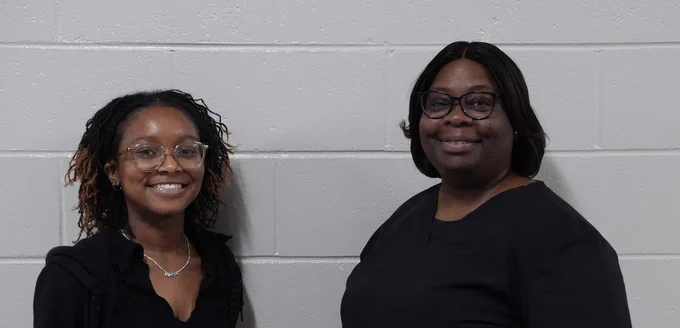 two ladies in black against a grey wall