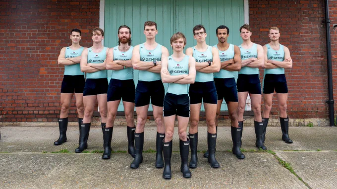 Men's Blue Boat crew standing in v-formation, arms crossed, ready to take Oxford on!