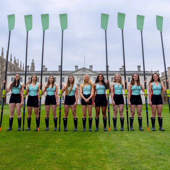 Women's Blue crew stand in a line with their blades held vertically.