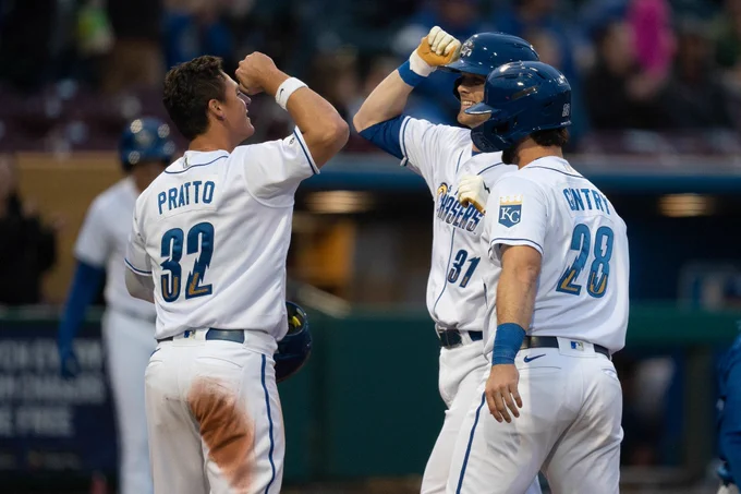 Grinning teammates exchanging elbow bumps at home plate. 