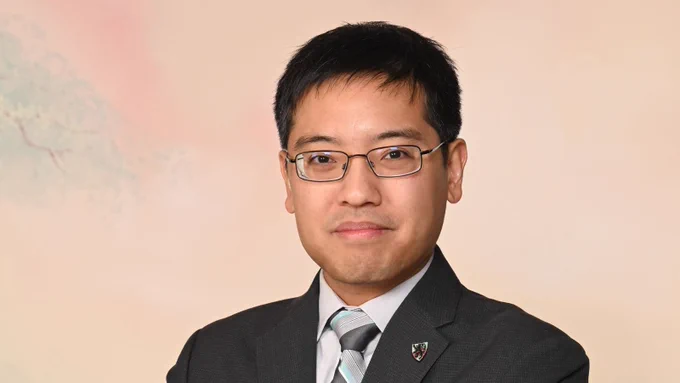 Photo of SEAS alum Eugene Beh, A.B./A.M. ‘09, wearing a grey suit and striped tie