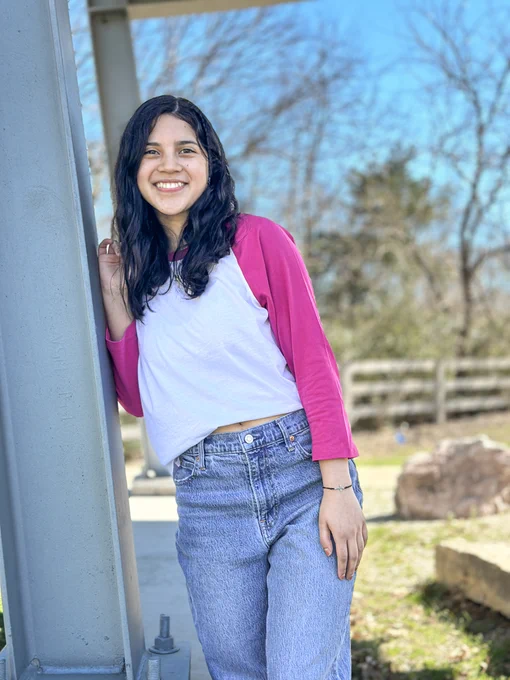 Photo of student leaning on a beam on campus. 