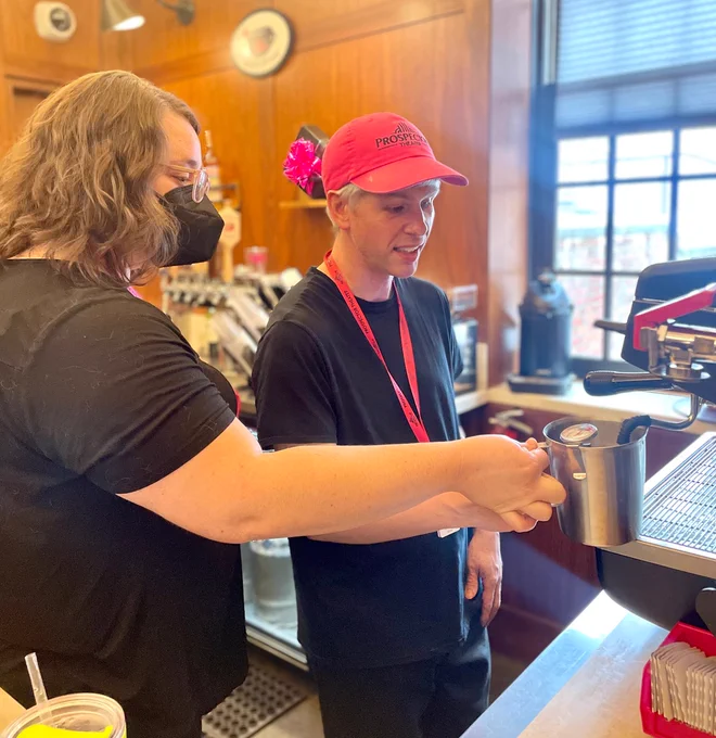 Christi teaches Aaron how to steam milk in the Heads Up Cafe.