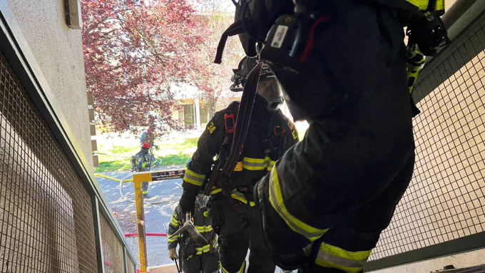 Three UCDFD firefighters in turnout gear climbing up the stairs of one of Solano Park’s units preparing to attack a simulated fire.