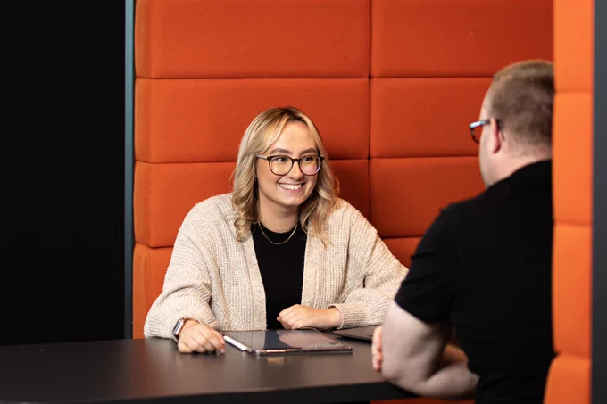 Photo of a BCU student and staff member talking in a study space in the Curzon library.