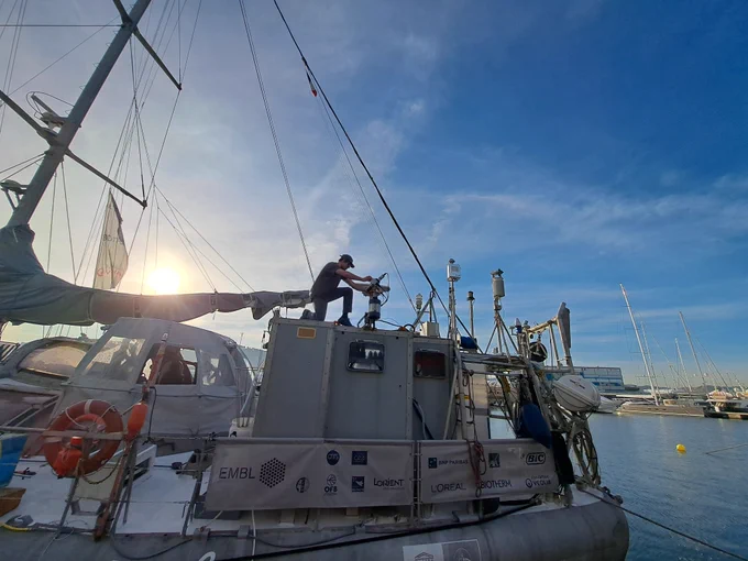 Tom Jordan on board the Tara installing equipment with the sun in the background