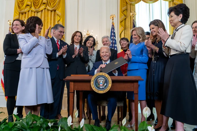 President Joe Biden signs an executive order to expand research on women's health care surrounded by leaders in women’s health.
