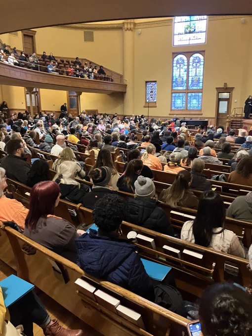 A large group of people listening to a state representative speaking. 