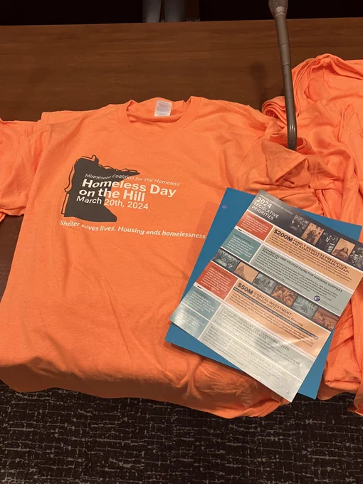 A brightly colored Homeless Day on the Hill T-Shirt on a table, with a print copy of the 2024 Legislative Priorities on top.