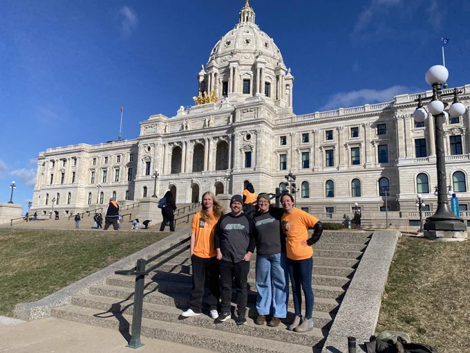 OSCS staff standing outside the State Capitol building in St. Paul on a sunny day.