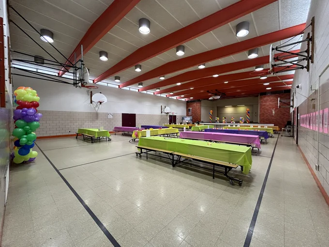 Cafeteria set up with lunch tables and balloons for literacy activities