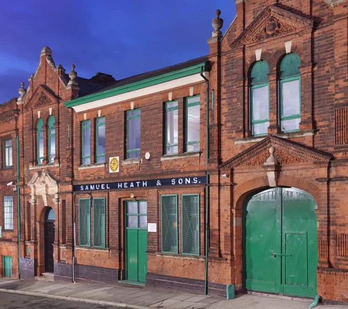 A photograph of a red brick Victorian building with text above the door reading 'SAMUEL HEATH & SONS'.