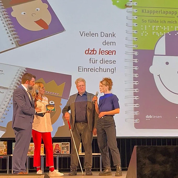 Vier Personen auf der Bühne (rechts Antje Mönnig und Thomas Kahlisch), im Hintergrund eine Leinwand mit dem Buch "Klapperlapapp - So fühle ich mich".