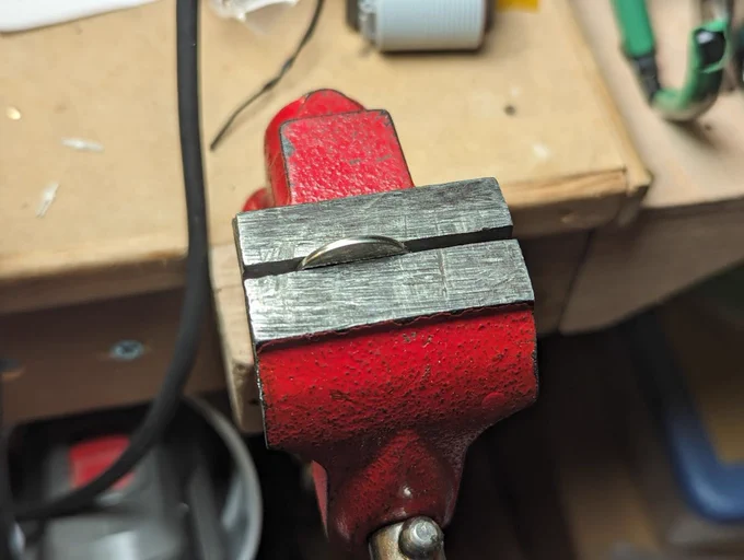 a coin cell in a metal vise. uhhh please don't do this
