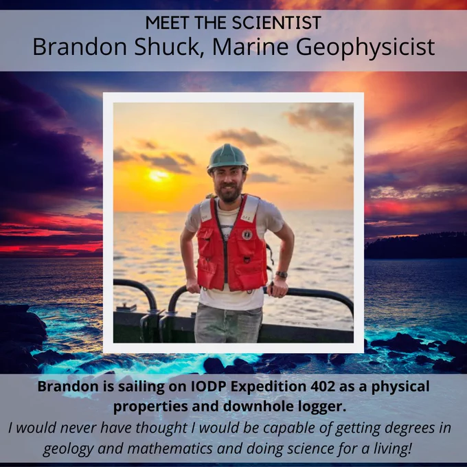 Background: sunset over the dark blue calm ocean, with a sunset that turns the sky colors of purple, blue, pink, and orange. Foreground, center: A man stands on a ship, leaning against the rails, smiling, wearing a white shirt, orange vest, and blue hard hat. 