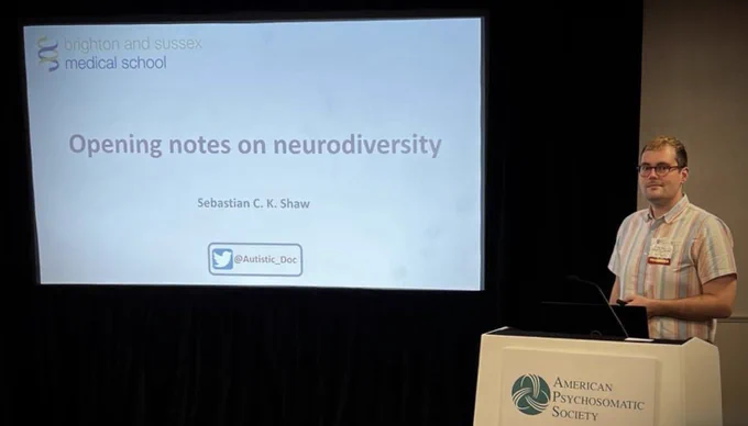 A photo of me at the presenter podium, showing the first slide of the opening part of our symposium. This reads “opening notes on neurodiversity”