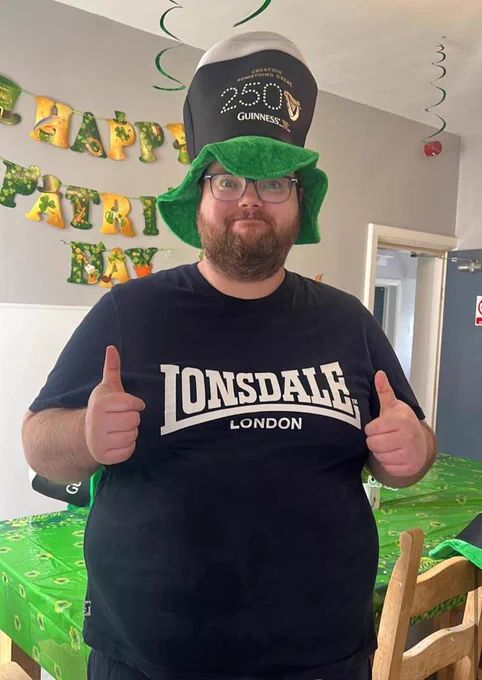 A resident giving a thumbs up and wearing a Guinness hat. 