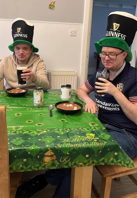 Two residents wearing Guinness hats and drinking a Guinness. 