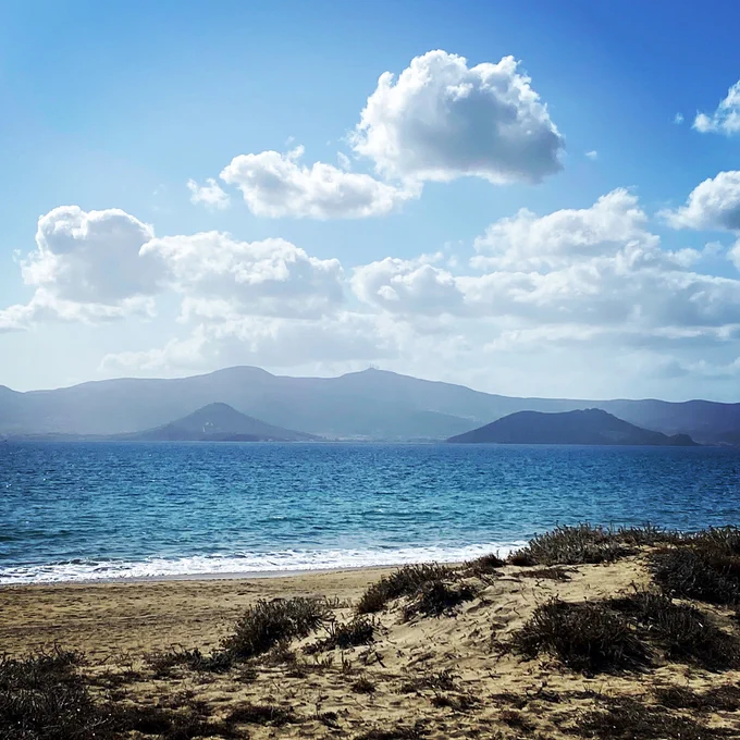 View of Paros from Naxos⁠ -- blue skies, blue waters, and puffy white clouds