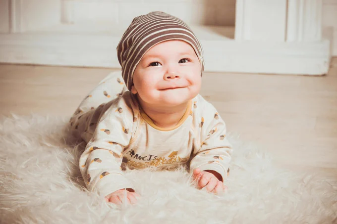 Baby lying on its front, looking up and smiling. 