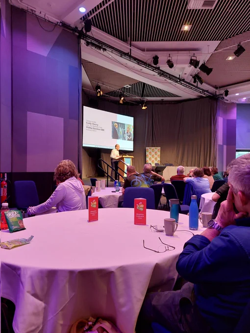 Closing address at conference. Phillip Darnton speaking on stage.