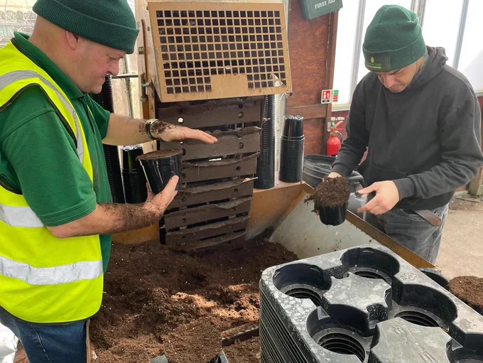 Two of Heaton Folds disabled students potting up soil ready to plant petunia plugs.