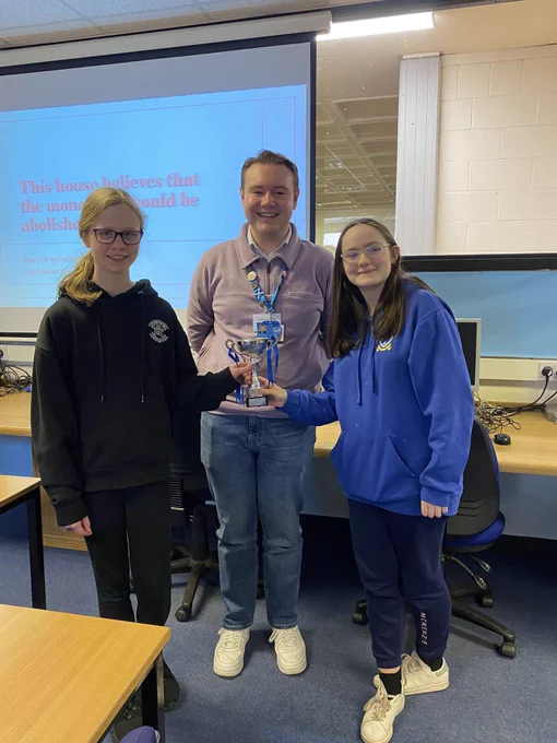 Angus Schools Debate Competition winners Chloe and Beau smiling and holding a trophy. Marcus Flucker MSYP is standing in-between them.
