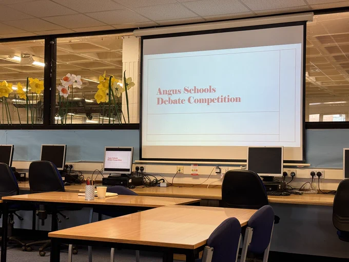 A projector screen showing a Angus Schools Debate Competition sign