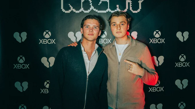 A picture of Nyhrox and his friend at GAME NIGHT: Stockholm in front of the photo wall.