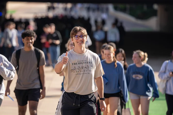 A student wearing a big event shirt gigging for a photo