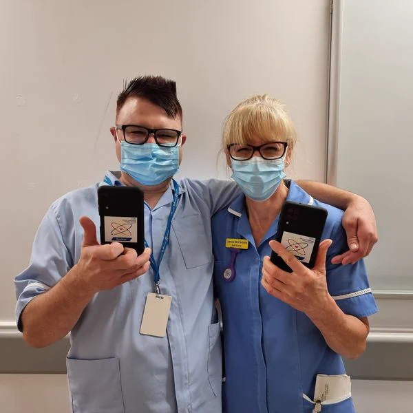 Clinical staff holding devices using Nucleus and giving a 'thumbs up' sign.