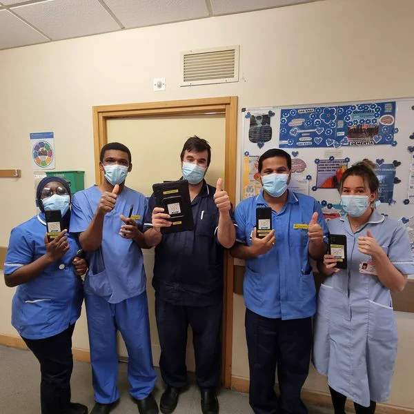 Clinical staff holding devices using Nucleus and giving a 'thumbs up' sign.