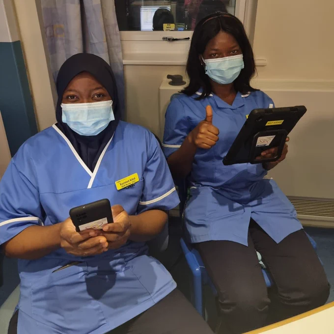 Clinical staff holding devices using Nucleus and giving a 'thumbs up' sign.