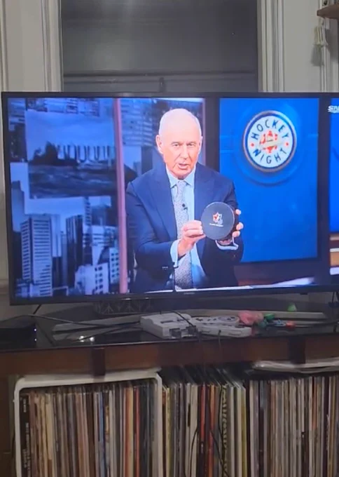 Ron MacLean holding up the blind hockey puck in studio during hockey night in canada