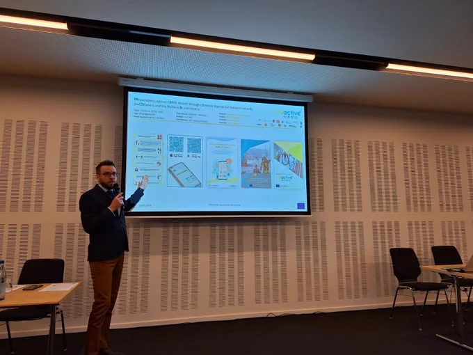 Man standing in front of a ppt slide, holding a micro and gesturing towards the projected slide
