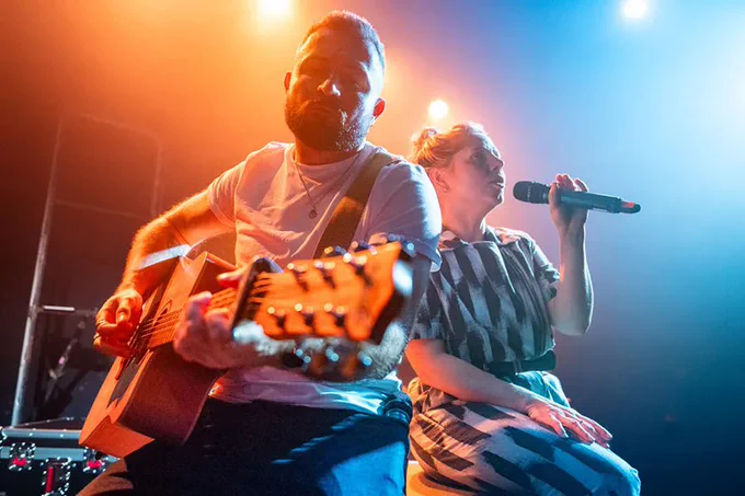 A photo of a man playing guitar next to a woman singing 