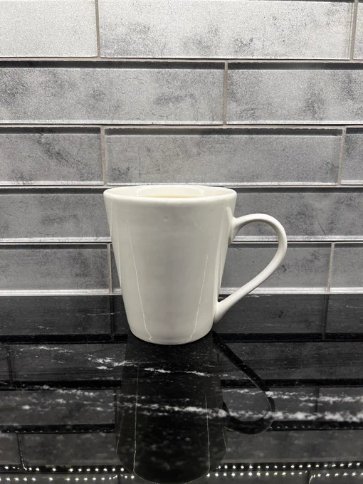 A porcelain mug sits on a black kitchen countertop near a gray glass tile backsplash. 

The mug has PG Tips Square teabags and this tea was a fantastic way to start the day ✅