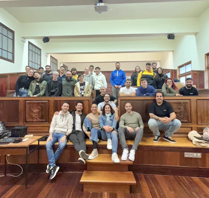 En una sala amplia de suelo y gradas de madera posan unas treinta personas del equipo de Lean Mind todas sonrientes mirando a cámara, algunas de pie y otras sentadas, muchas rodean con su brazo a la compañera y compañero a su lado