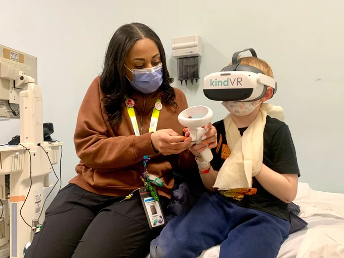 A Child Life Specialist at Michael Garron Hospital helping a young patient play a virtual-reality game. 